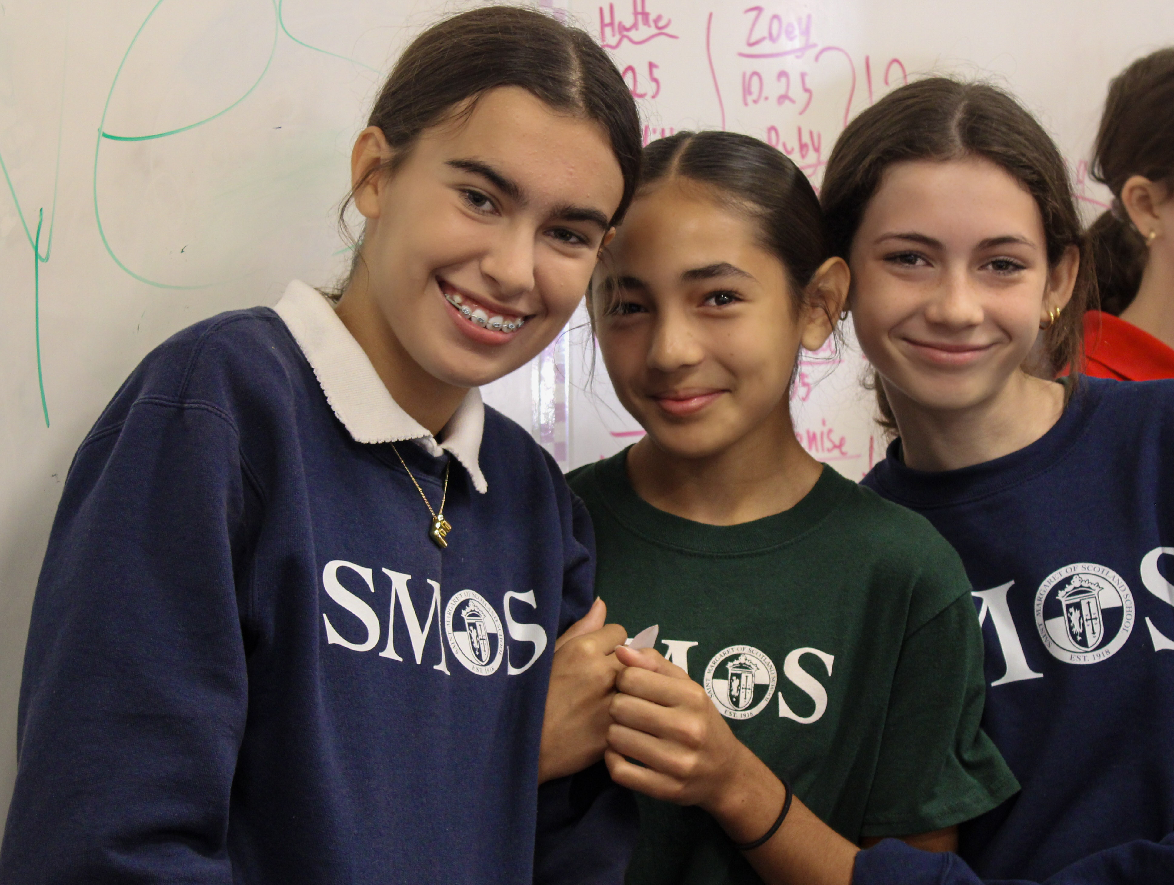 Three students in uniform smiling