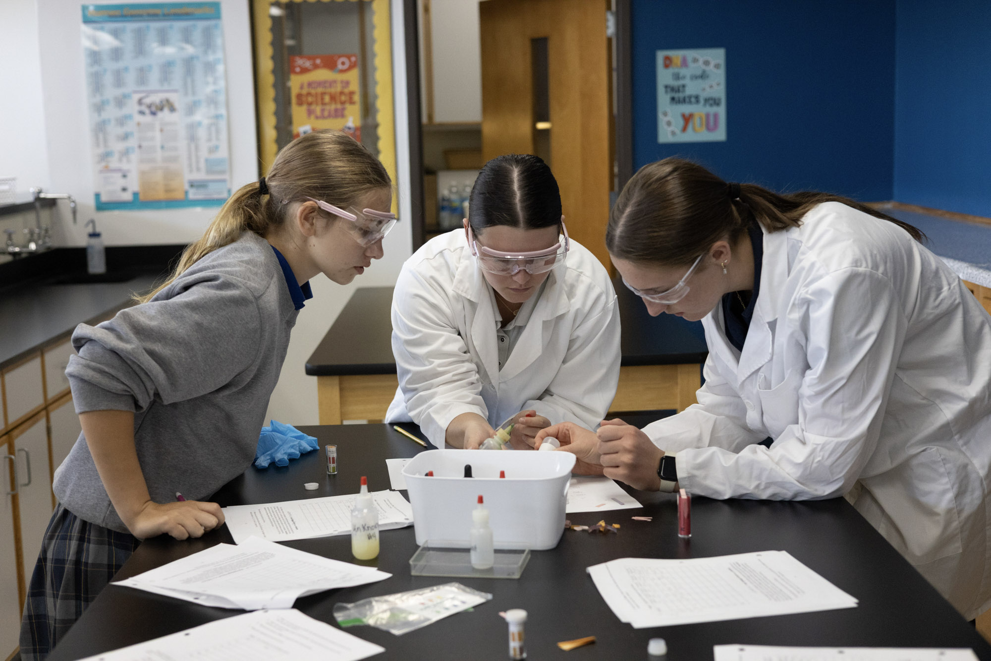 Three students in lab coats working on a project