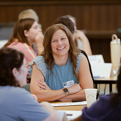 Teacher Julia McNead sitting and discussing with her table at New Teacher Orientation