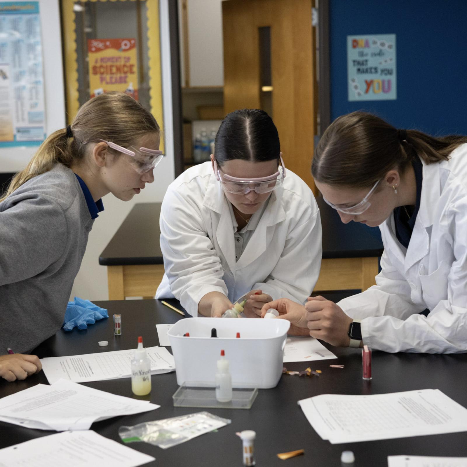 Three students in lab coats working on a project